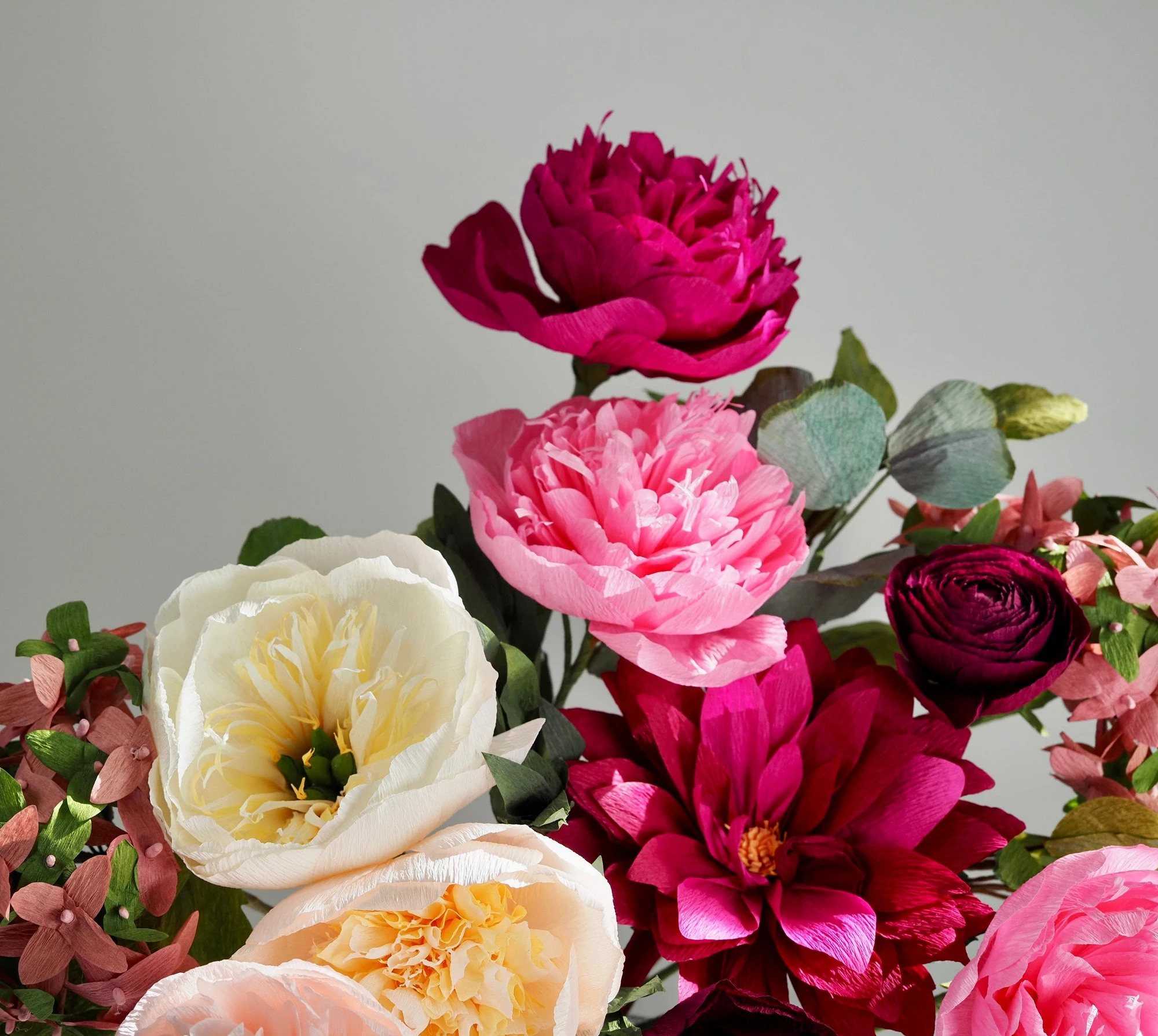 Hands crafting Italian crepe paper flowers with scissors and petals
